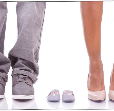 Photo of a man and woman's feet with baby shoes between them