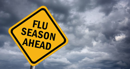 Photo of yellow road sign against gray cloudy sky that says flu season ahead