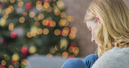 Blonde woman looking sad with Christmas tree in background