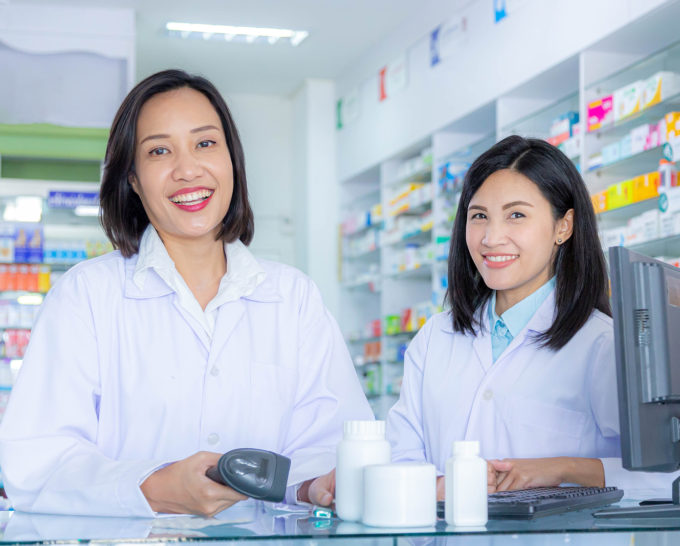 Two asian pharmacists working in a pharmacy drugstore. Health care and medical concept.Pharmacist scanning barcode of medicine drug in a pharmacy drugstore.