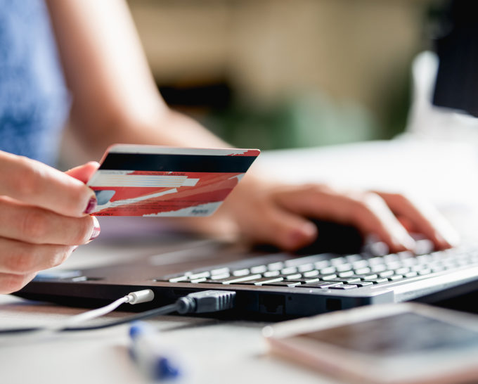 White woman buying online with credit card. Online shopping. Woman shopping online. Female hands holding credit card using laptop computer to shop online. Online shopping. Paying with credit card online.