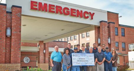 Photo of people standing outside of GHS emergency entrance holding a giant check
